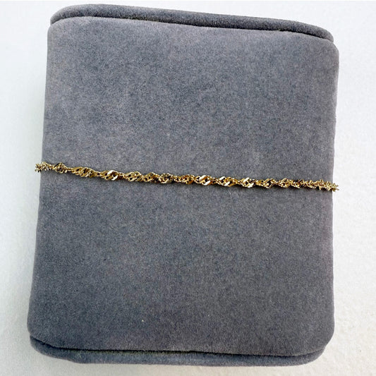 Gold chain bracelet on a gray jewelry display box